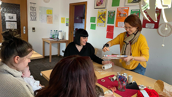 Mütter mit Kindern und Mitarbeiterinnen sitzen in der Wohngruppe am Tisch.