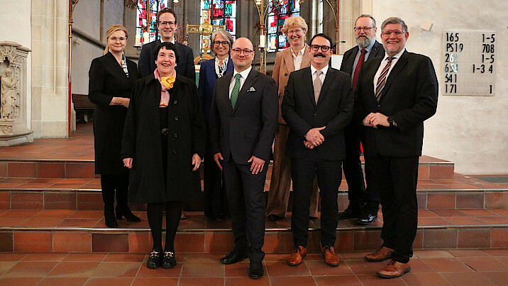 In der Nürtinger Stadtkirche St. Laurentius stehen die Beteiligten des Gottesdienstes auf einer Treppe und schauen lächelnd in die Kamera.