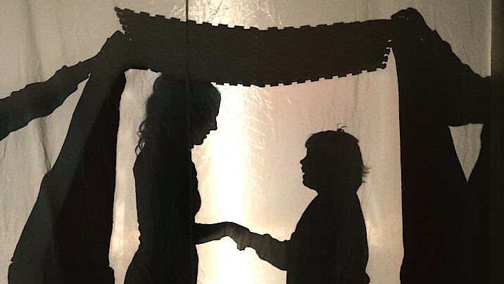 Bild zeigt eine große und eine kleine Person beim Schattentheater