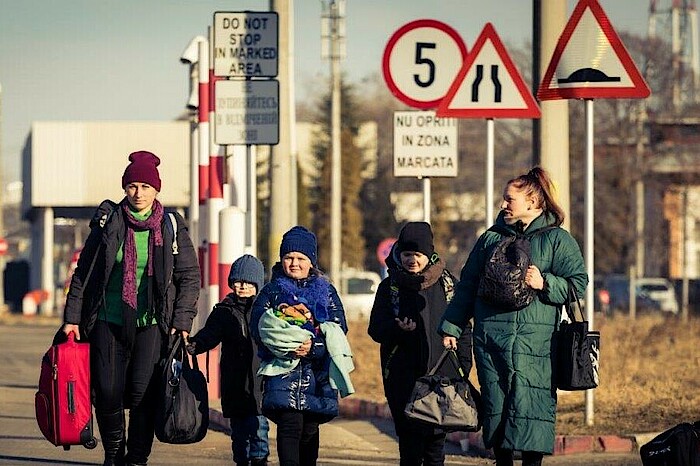 Zwei Frauen und drei Kinder sind auf der Flucht weg aus der Ukraine. Sie tragen Gepäck und sind den kalten Temperaturen entsprechend angezogen. 