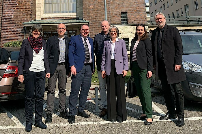 Vier Männer und drei Frauen der Delegation stehen in der Sonne vor einer Kirche in der Slowakai.