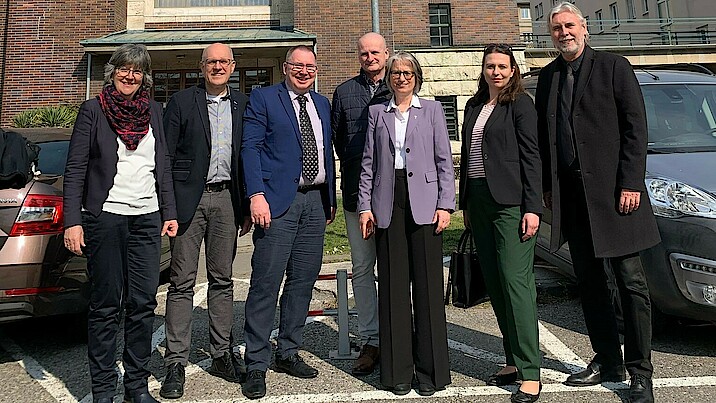 Vier Männer und drei Frauen der Delegation stehen in der Sonne vor einer Kirche in der Slowakai.