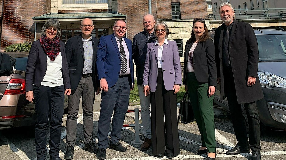 Vier Männer und drei Frauen der Delegation stehen in der Sonne vor einer Kirche in der Slowakai.